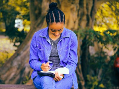 selective focus photography of woman reading book while sitting at bench