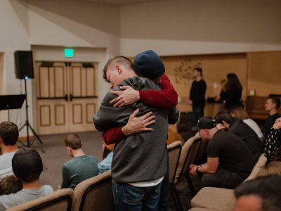 man in gray sweater carrying woman in black jacket