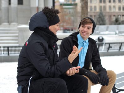 two men talking while sitting on bench