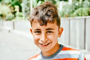 boy in orange and gray crew neck shirt smiling